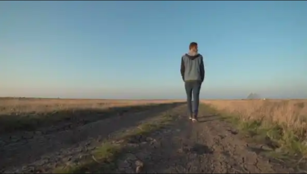 Young Man Walking Away Down a Rural Road (Stock Footage)